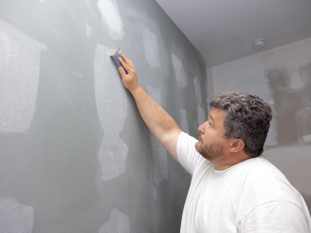 a man sanding a wall